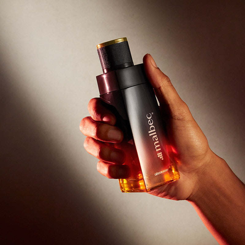 Malbec X Eau de Toilette 100ml Perfume Malbec com tampa preta e base amarela segurado por uma mão