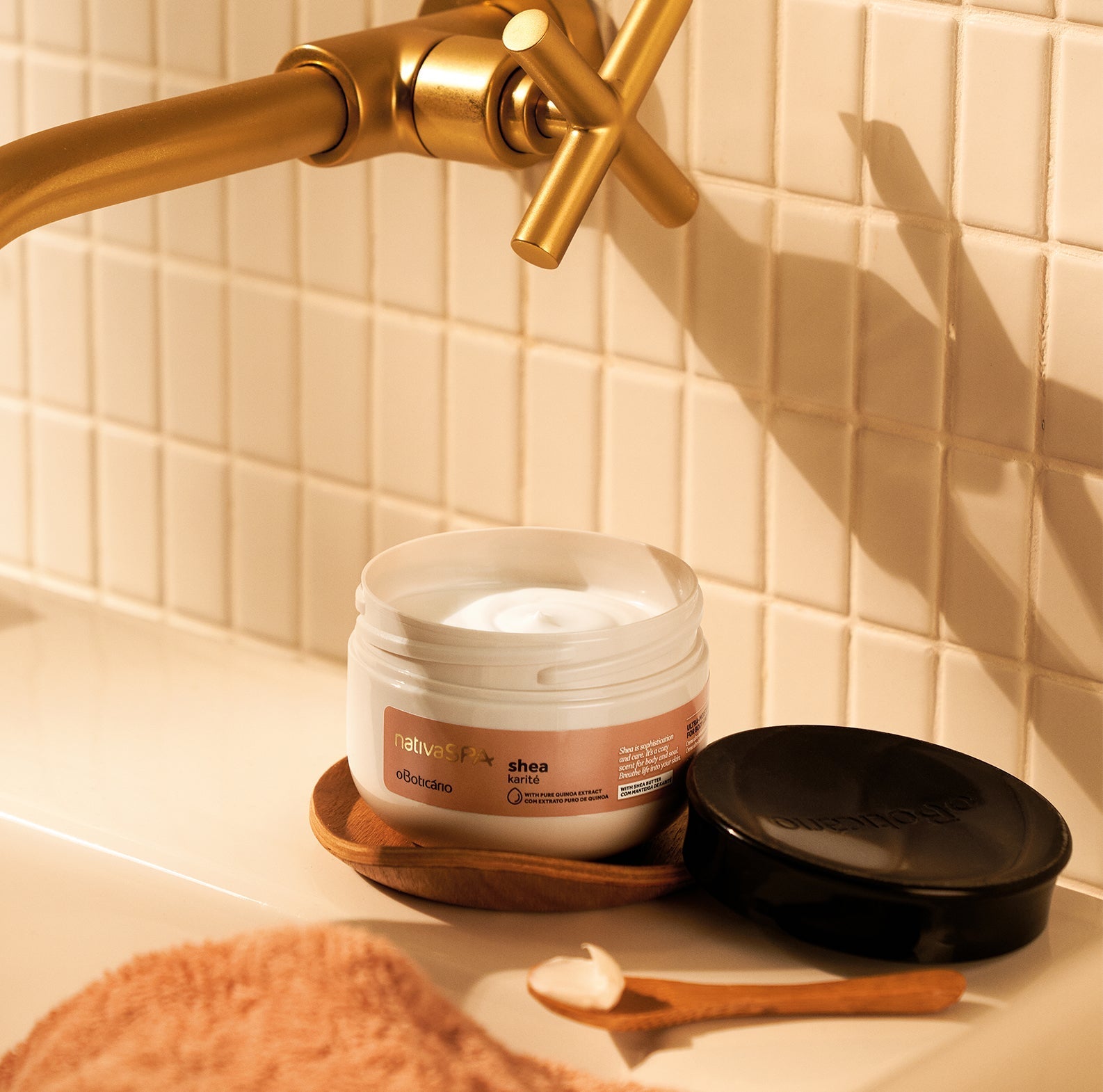 Nativa SPA Creme Ultra Hidratante Karité 200g Frasco aberto de creme corporal Naturalist com tampa preta e colher de madeira numa bancada com torneira dourada