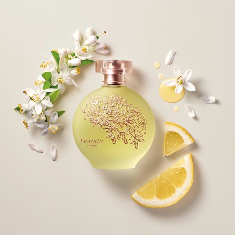 Floratta L'Amore Eau de Toilette 75ml Frasco redondo de perfume Floratta com flores brancas e fatias de limão sobre fundo bege