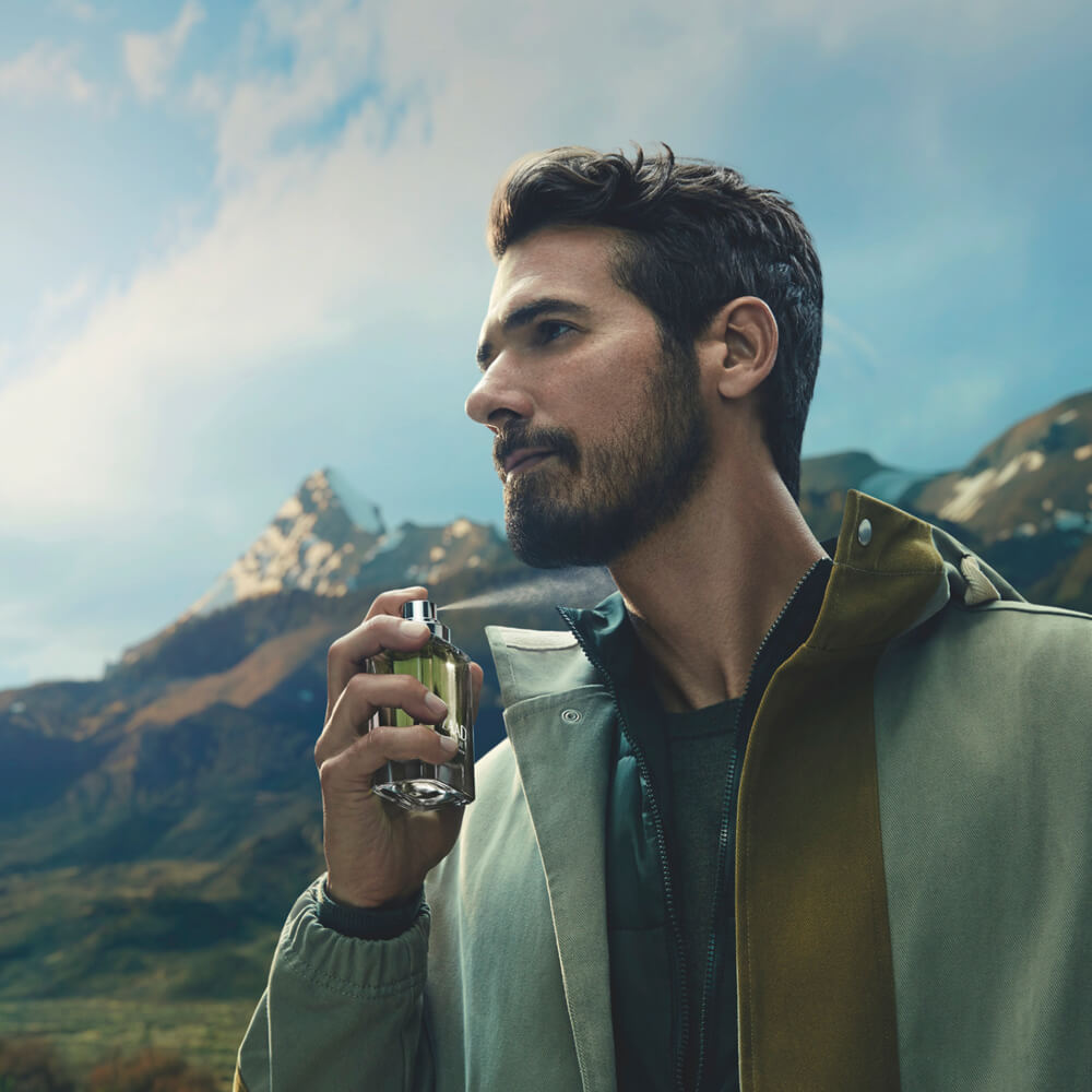 Zaad Venture Eau de Parfum 95ml Homem com casaco verde-cinzento segurando frasco de perfume ao ar livre nas montanhas