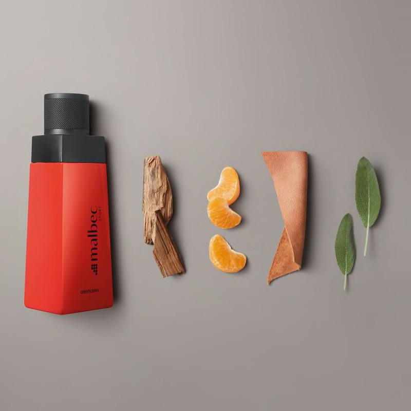 Malbec Sport Eau de Toilette 100ml Frasco de perfume vermelho com elementos naturais ao lado sobre fundo cinza claro