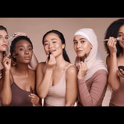 Cinco mulheres diversas aplicando maquilhagem sobre fundo bege.