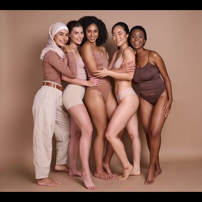 Cinco mulheres posando com roupas interiores e pijamas em tons neutros num fundo bege