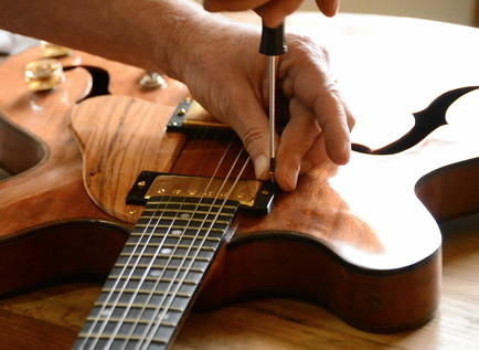 Guitarras - Mudança de cordas e manutenção Pessoa a afinar guitarra elétrica de corpo oco em madeira com chave de fendas