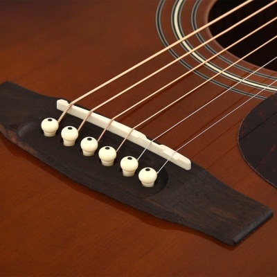 Guitarra acústica castanha vista ao detalhe do cavalete e cordas