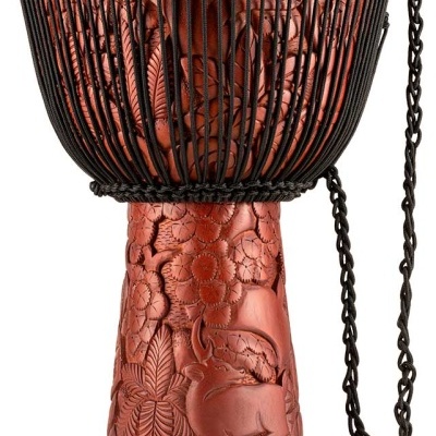 Djembe de madeira vermelha trabalhada com cordas pretas e pele clara.