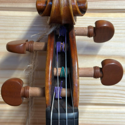 Braço de violino em madeira com cravelhas e cordas, sobre fundo de madeira clara