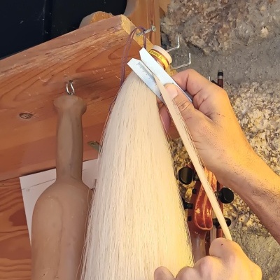 Material branco pendurado com mãos a manipular ferramenta, base de garrafa castanha e parede rugosa ao fundo