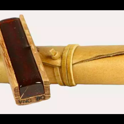 Rolo de papel amarelo enrolado com cordão e carimbo de madeira castanho escuro