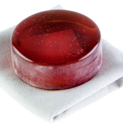 Doce redondo translúcido vermelho em tecido cinzento