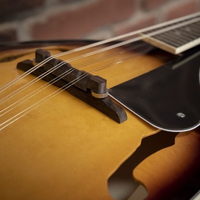 Instrumento de cordas em madeira amarela e castanha com cordas e ponte escura