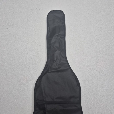 Capa preta para guitarra sobre mesa de madeira contra parede branca.