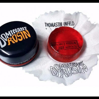 Recipiente preto com breu vermelho para arco musical sobre pano branco