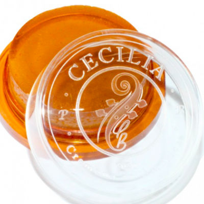 Recipiente de plástico com tampa transparente e pomada laranja, texto 'CECILIA' na tampa