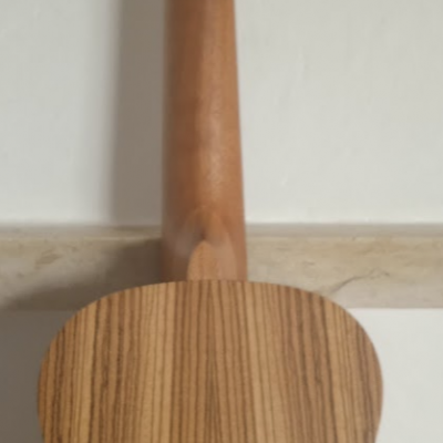 Parte traseira de violão de madeira clara com braço e tarraxas