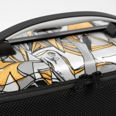 Mala de viagem com padrão amarelo, preto e cinza e pega preta arredondada