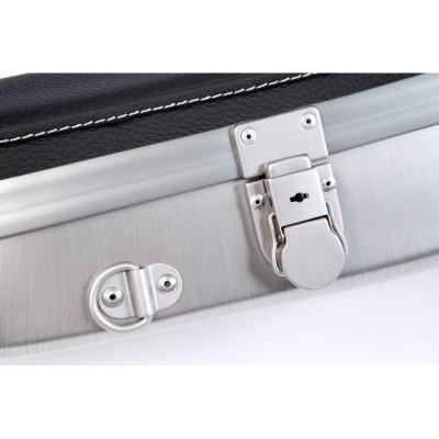 Fecho metálico prateado e detalhe em couro preto com costura branca numa mala rígida sobre fundo branco