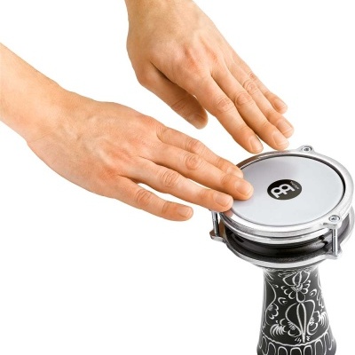 Tambor darbuka preto com decoração branca e pele sintética branca na cabeça com duas mãos a tocar