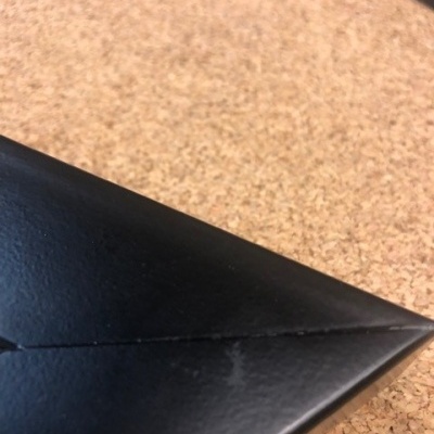 Borda triangular de capa preta com costura sobre cortiça