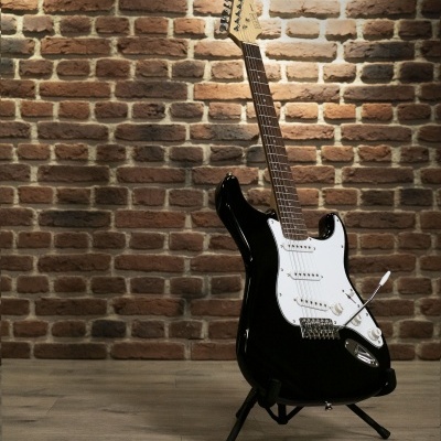 Guitarra elétrica preta com pestana branca e suporte