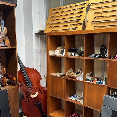 Instrumentos musicais e acessórios organizados em estantes de madeira numa sala interior