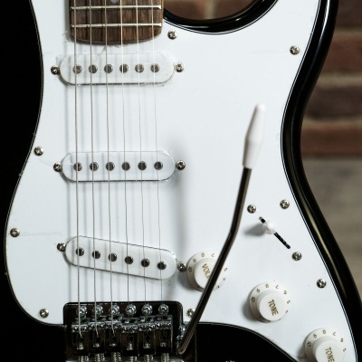 Guitarra elétrica preta com captadores brancos e ponte metálica