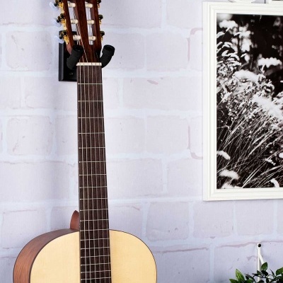 Guitarra clássica pendurada numa parede com decoração próxima