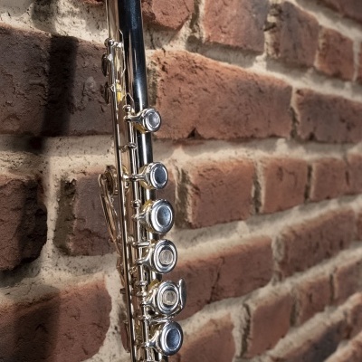 Flauta transversal prateada pendurada numa parede de tijolos