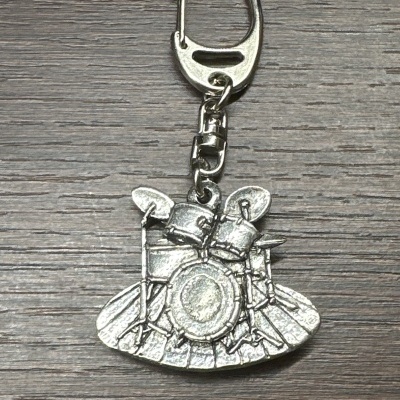 Porta-chaves metálico com pendente em forma de bateria sobre madeira escura