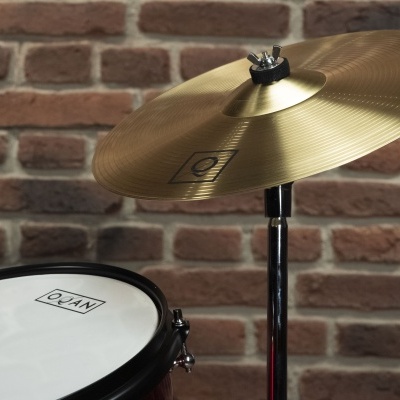 bateria musical com prato metálico dourado e pele de tambor branca QIAN com parede de tijolos ao fundo