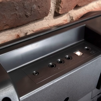 Painel traseiro de equipamento preto com entradas de áudio e vídeo e parede de tijolos