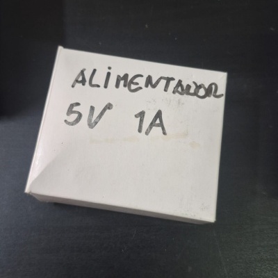 Embalagem branca com texto escrito à mão ALIMENTADOR 5V 1A