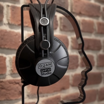 Fones de ouvido pretos QOH30 Studio da marca QOAN numa estrutura metálica preta em forma de rosto