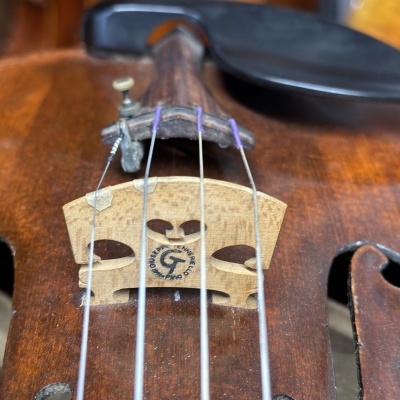 Violino castanho com ponte marcada e cordas metálicas