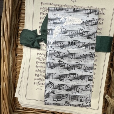 Marcador de páginas com pauta musical e fita verde sobre cesto de verga