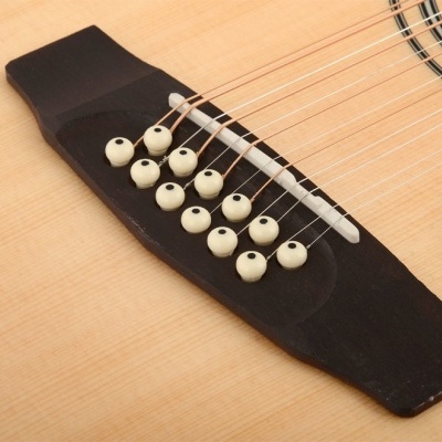 Detalhe da ponte e cordas de uma guitarra acústica em madeira clara