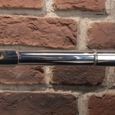 Flauta metálica prateada contra parede de tijolos vermelhos