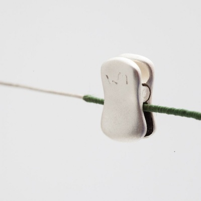 Prego metálico prateado com texto gravado em fio verde e branco