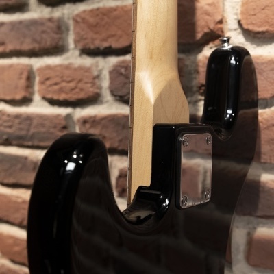 Parte traseira de guitarra elétrica preta contra parede de tijolos