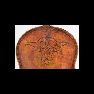 Parte traseira de instrumento musical de madeira com padrão gravado a negro.