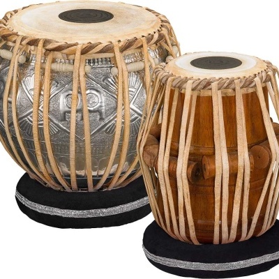 Conjunto de tambores tabla indianos de metal e madeira com peles e cordas, em almofadas pretas.