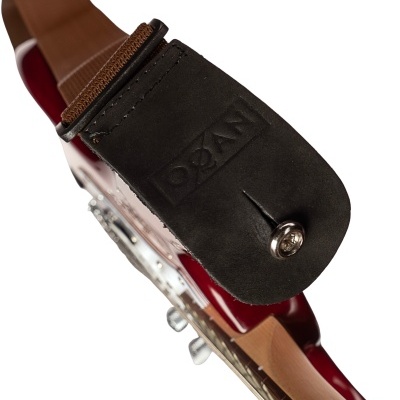 Correia de guitarra castanha com extremidade em couro preto e botão metálico, sobre guitarra vermelha