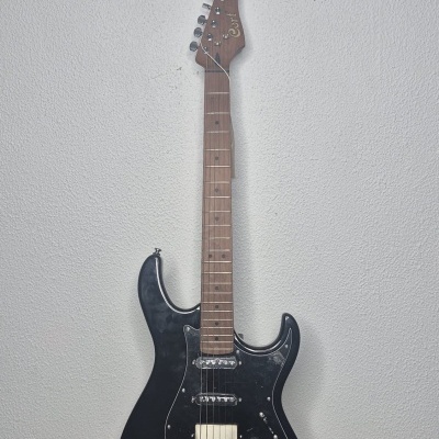 Guitarra elétrica preta com braço de madeira clara e texto Cort na cabeça