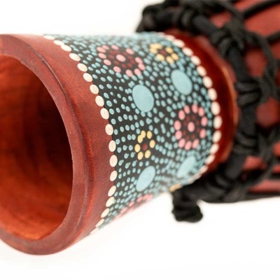 Tubo de madeira decorado com padrão pontilhado colorido e cordas pretas trançadas