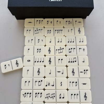 Domino musical branco com símbolos musicais e caixa preta com texto