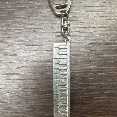 Chaveiro metálico retangular com a palavra 'Billionaire' em relevo