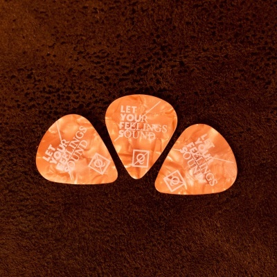 Três palhetas laranjas marmoreadas com texto branco sobre superfície escura