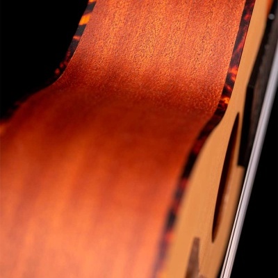 Guitarra acústica de madeira castanha com bordas escuras, em fundo preto