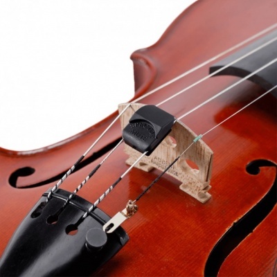 Violino castanho com acessório preto nas cordas próximo ao cavalete
