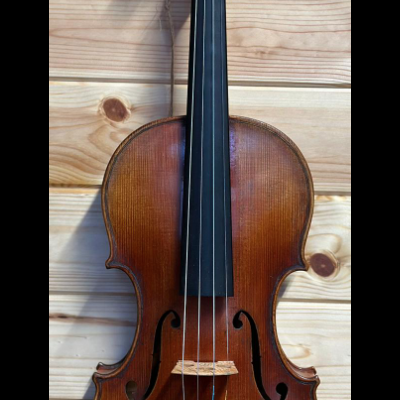 Violino de madeira castanha pendurado numa parede de madeira clara